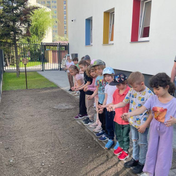 Dzieci stoją w szeregu i sieją nasiona