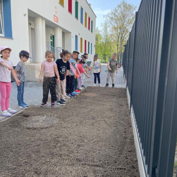 Dzieci stoją w szeregu i sieją nasiona